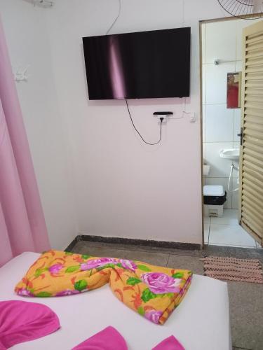 a room with a bed with a television on the wall at Hotel da Creuza in Goiânia