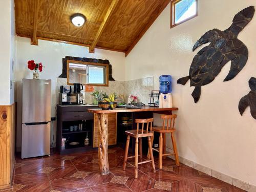 a kitchen with a refrigerator and a counter with stools at PARAÍSO Sunset Bungalows in Hanga Roa