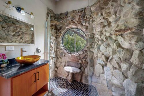 Baño de piedra con lavabo y pared de piedra en Riverfront & Jacuzzi. 8th wonder of the world., en Rivas