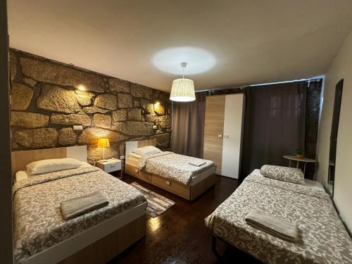 een slaapkamer met 2 bedden en een stenen muur bij Invited to Porto in Porto