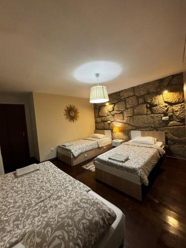 een slaapkamer met 2 bedden en een stenen muur bij Invited to Porto in Porto