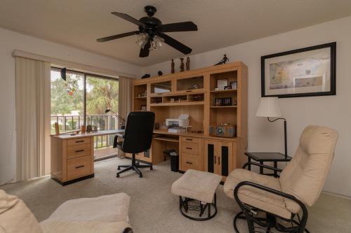 een woonkamer met een bureau, stoelen en een ventilator bij Sun Eagle Condo! Cozy condo with workspace and community pool! in Bradenton
