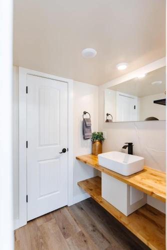 a bathroom with a white sink and a white door at Zion Adventure Tiny Home, Cozy Fireplace & Deck in Apple Valley