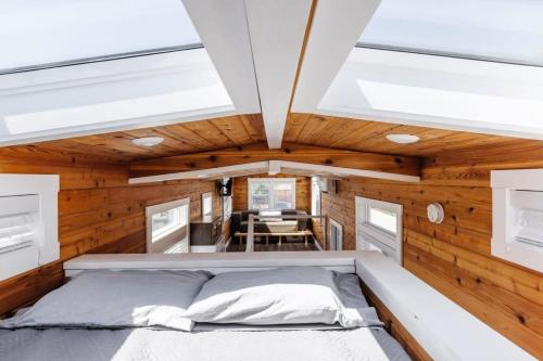 Bett in einem Zimmer mit Holzwänden und Oberlichtern in der Unterkunft Harrington Tiny House in Apple Valley