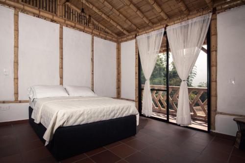 a bedroom with a bed and large windows at Guaduas de Jade Casa campestre in La Mesa