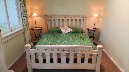 ein Schlafzimmer mit einem Bett mit einer grünen Bettdecke und zwei Lampen in der Unterkunft The Old Dairy Factory in Norsewood