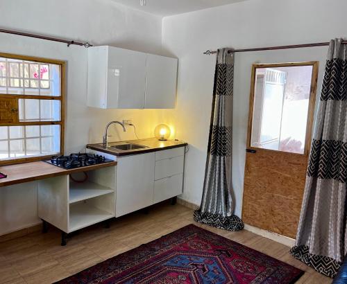 a kitchen with white cabinets and a sink and a window at Amas Bungalow with internett in Batukunku