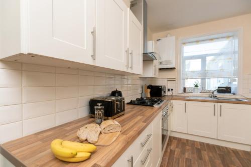 a kitchen with white cabinets and bananas on a counter at Miners cottage DH1 Bungalow Free Parking Longstay in Sheepscar