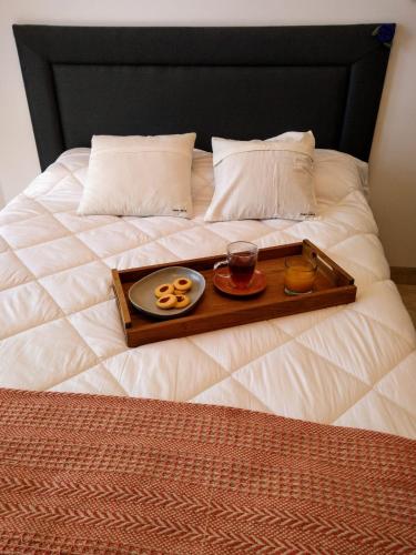 a tray with food and drinks on a bed at Avenida Premium: Confort y Vistas Excepcionales in San Salvador de Jujuy