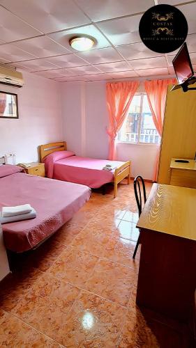 a room with two beds and a desk and a table at Hotel y Restaurante Costas in Fortuna