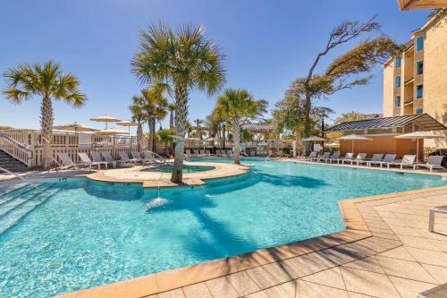 a swimming pool with palm trees in a resort at Omni Hilton Head Oceanfront Resort in Hilton Head Island