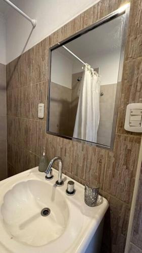 La salle de bains est pourvue d'un lavabo blanc et d'un miroir. dans l'établissement Departamento Carosini. Amplio familiar., à Concepción del Uruguay