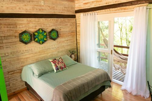 a bedroom with a bed and a sliding glass door at Chalé Esmeralda na Amarte perto do Templo Budista in Três Coroas