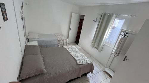 a small bedroom with two beds and a window at Pousada Mar & Sol in Fortaleza