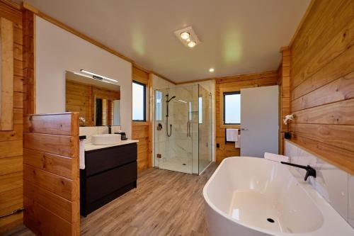 ein Badezimmer mit einer großen Badewanne und einer Dusche in der Unterkunft Deerbrooke Kaikōura Chalets - Chalet 1 in Kaikoura