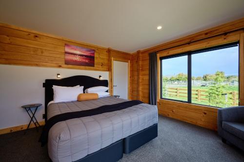 um quarto com uma cama e uma grande janela em Deerbrooke Kaikōura Chalets - Chalet 1 em Kaikoura