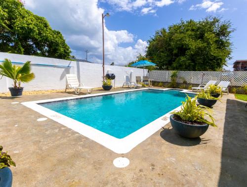 a swimming pool in a backyard with chairs and plants at Beach House In Crown Point- walk to the beach in Bon Accord