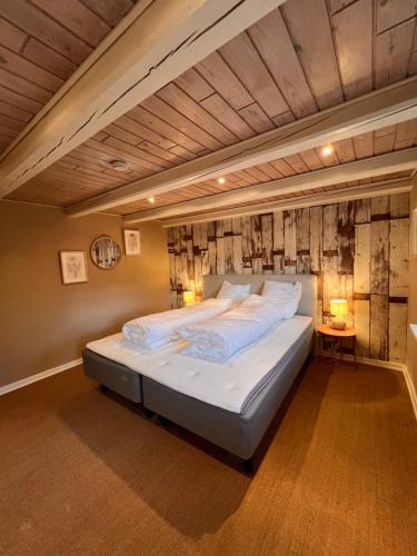 a large bed in a room with a wooden ceiling at Charmerende stråtag strå hus (med Vildmarksbad) in Give