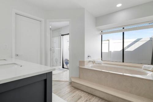 un bagno bianco con vasca e una grande finestra di Tropical Tranquility! Luxury pool home with lakefront view just minutes from the beach! a Bradenton