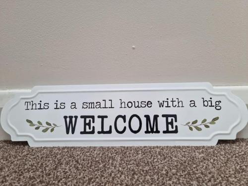 a small house with a big welcome sign on a wall at Modern loft with country views in Conlig