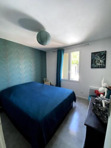 une chambre avec un lit bleu et une fenêtre dans l'établissement Roxy House, au Château-dʼOléron