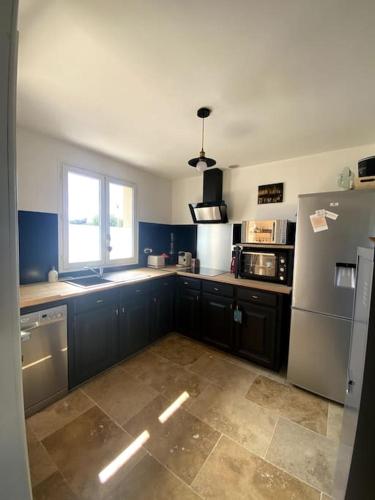 une cuisine avec des placards bleus, un réfrigérateur et une fenêtre dans l'établissement Roxy House, au Château-dʼOléron