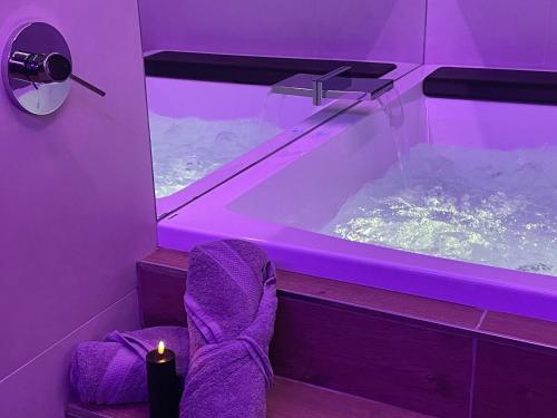 a purple room with a bathtub with a chair and a candle at Love room - Intimate Escape in Arlon