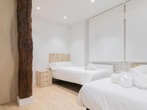 twee bedden in een kamer met witte muren bij La cruz cozy apartment by Next Stop Bilbao in Bilbao