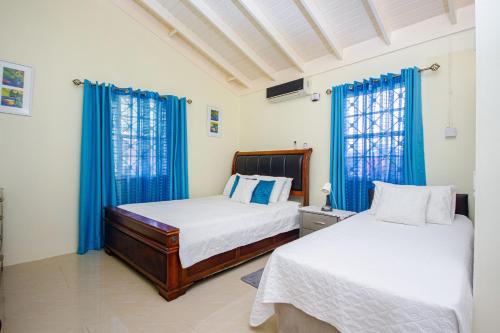 2 camas en una habitación con cortinas azules en Ocho Rios Drax Hall Country Club 2 Bed Villa Getaway, en Mammee Bay