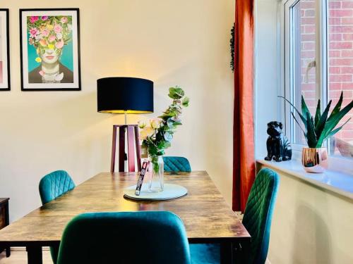 a dining room table with a vase of flowers on it at Hidden Gem in Chelmsford by Artisan Stays I Weekly or Monthly Stay Offer I Free Parking I Sleeps 5 in Chelmsford