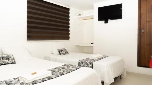 a room with two beds and a flat screen tv at ALOJAMIENTO MOON in Valledupar
