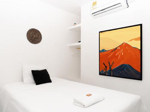 Cette chambre comprend un lit blanc orné d'une peinture murale. dans l'établissement ALOJAMIENTO MOON, à Valledupar