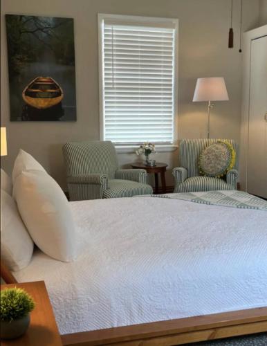 a bedroom with a large bed with two chairs at Large, Bright Suite Kitchenette in Ligonier