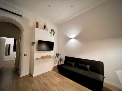 een woonkamer met een zwarte bank en een tv bij Angelina's home - Milano Bovisa in Milaan