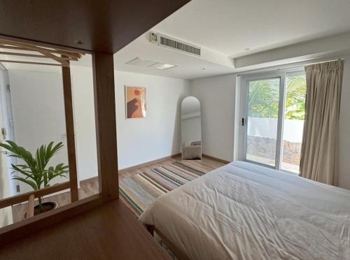 een slaapkamer met een bed en een groot raam bij Boho chic sea view apartment in Kata in Kata Beach