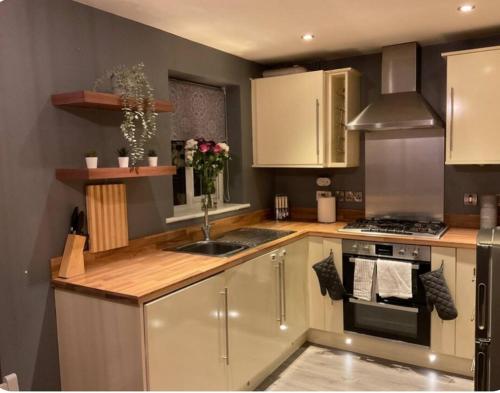 a kitchen with white cabinets and a sink and a stove at The Westfield in Liversedge