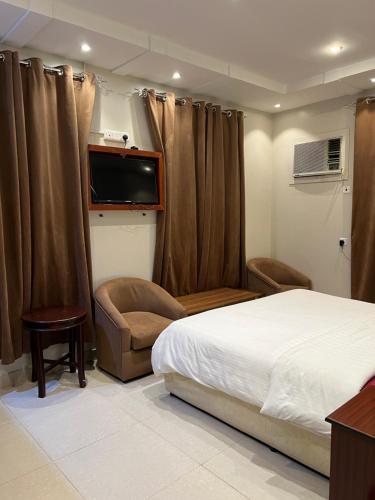 a bedroom with a bed and a flat screen tv at ريحانة الهدا للوحدات السكنية in Al Hada