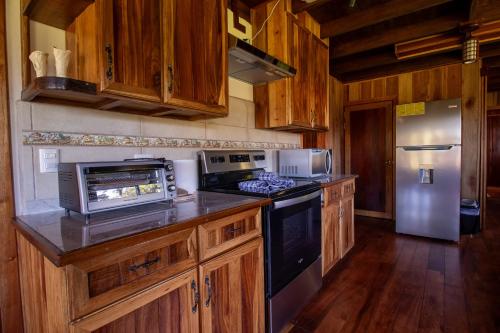 a kitchen with wooden cabinets and a stove and refrigerator at Mountain Wonders Chalet in Monteverde Costa Rica