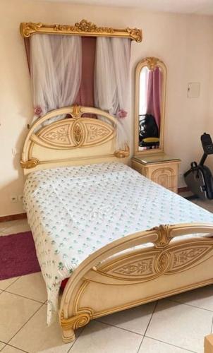 ein Schlafzimmer mit einem Bett mit Goldrahmen und einem Spiegel in der Unterkunft Appartement duplex in Asnières-sur-Seine