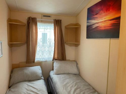 una piccola camera con due letti e una finestra di BelLa VistA - Holiday Home On The Beach a Clacton-on-Sea