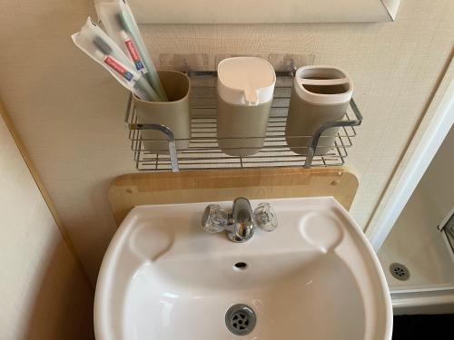 a bathroom with a sink and a shelf with toothbrushes at BelLa VistA - Holiday Home On The Beach in Clacton-on-Sea