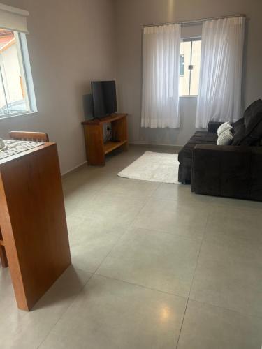 ein Wohnzimmer mit einem Sofa und einem TV in der Unterkunft Chales Maria Flor in Gonçalves