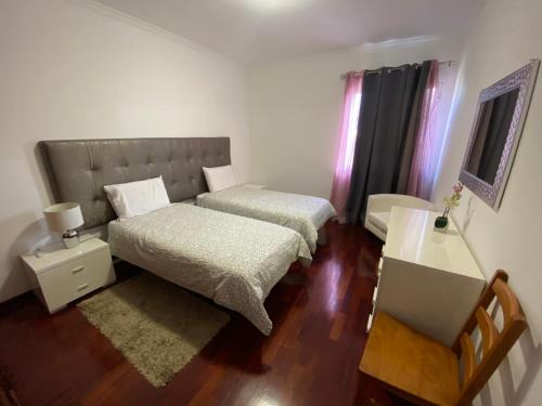 um pequeno quarto com 2 camas e uma secretária em Santa Luzia Apartment no Funchal