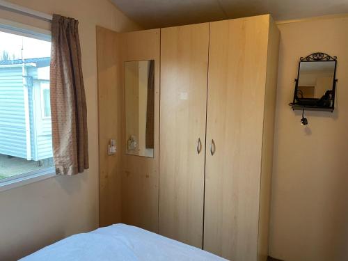 a bedroom with a wooden cabinet and a window at BelLa VistA - Holiday Home On The Beach in Clacton-on-Sea