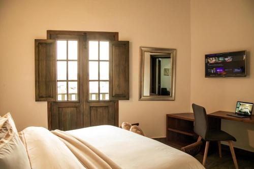 1 dormitorio con cama, escritorio y ventana en Santa Lucía Casa Hotel, en Villa de Leyva