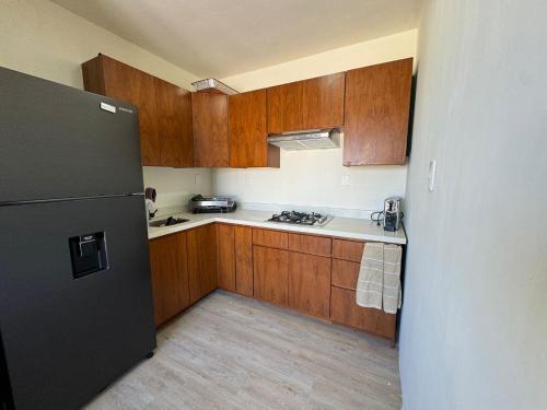 a kitchen with wooden cabinets and a black refrigerator at Casa Arsha Beachfront Paradise in Santa Clara