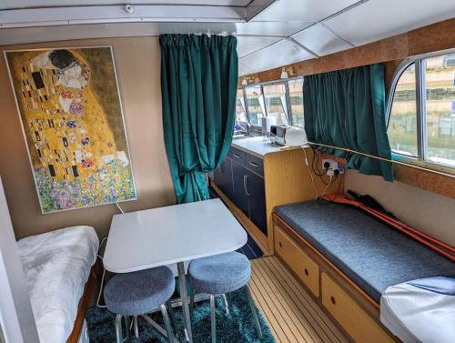 チェルムスフォードにあるUnique Boat in Chelmsford cityのデスク、テーブル、椅子が備わる小さな客室です。