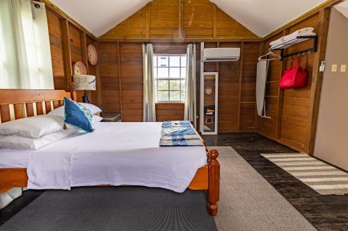 ein Schlafzimmer mit einem Bett in einem Zimmer mit Holzwänden in der Unterkunft Beach Studio in Crown Point in Bon Accord