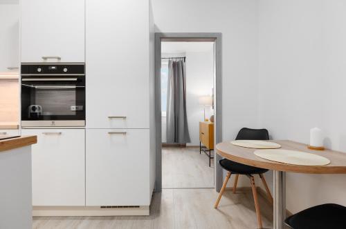 a kitchen with white cabinets and a wooden table at 2 bedrooms apartment with kitchen near the subway in Prague