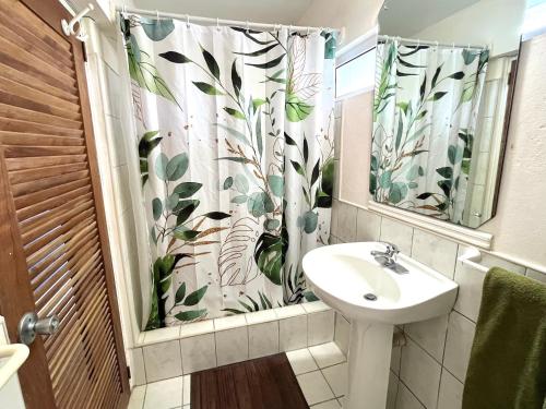baño con lavabo y cortina de ducha en Bacolet Beach House- 5 Bedrooms/ 5 Bathrooms en Bacolet